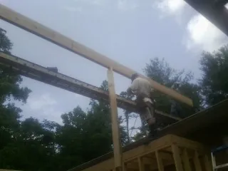 Carpenter setting a ridge beam over a new addition frame — Ice Dam Removal by Roofing Brothers in Wittman