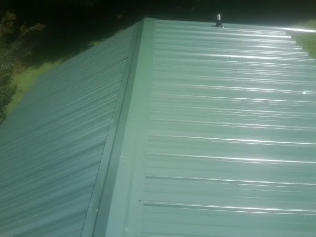 New green metal panels meeting at the ridge of a roof — Flat Roof Repair work by our crew in Wittman