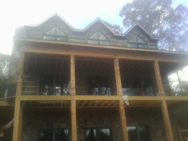 Dormers and porch framing on a large log home under construction — Roof Coating work by our crew in Wittman