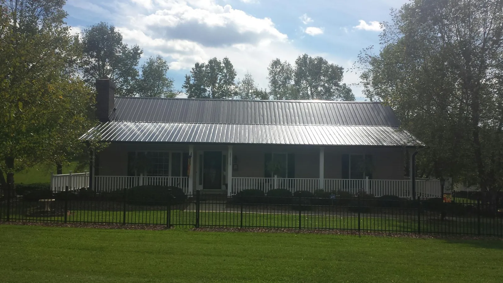 Gray metal roof on a brick ranch with a full width front porch — Gutter Guard Installation work by our crew in Wittman