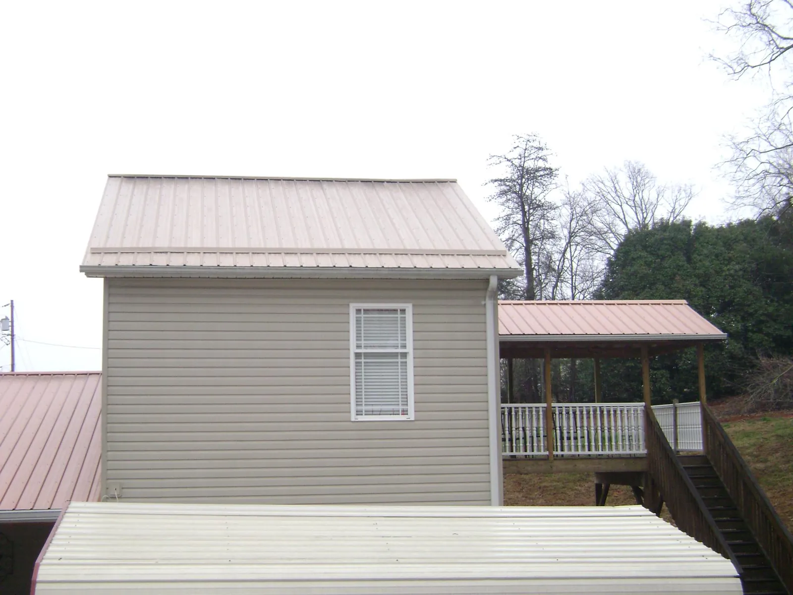 Tan metal roofs on a two story addition and attached porch, from a Roof Replacement job in Wittman