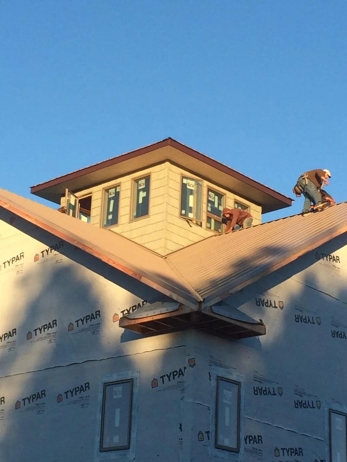 Roofers working around a rooftop cupola on a new metal roof at sunset — Roof Waterproofing in Wittman by Roofing Brothers